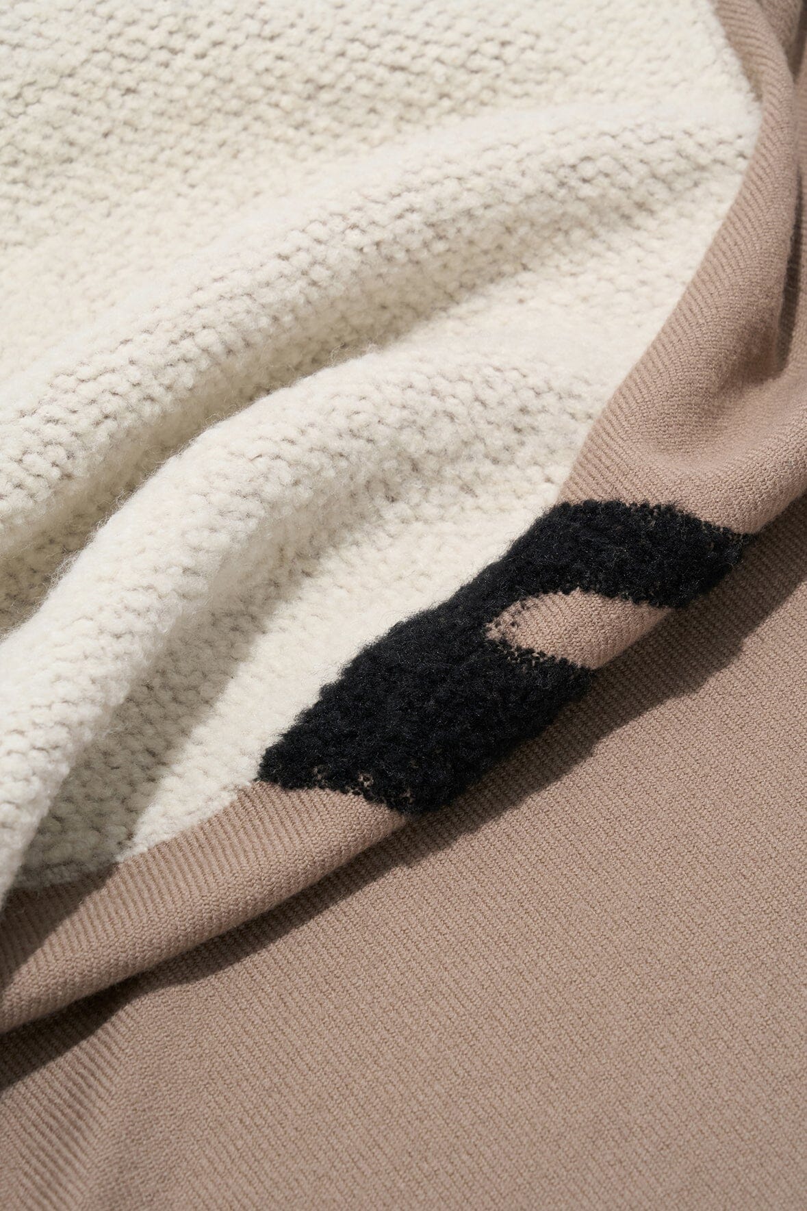 Sherpa-textured underside of truffle taupe throw with black paw print design
