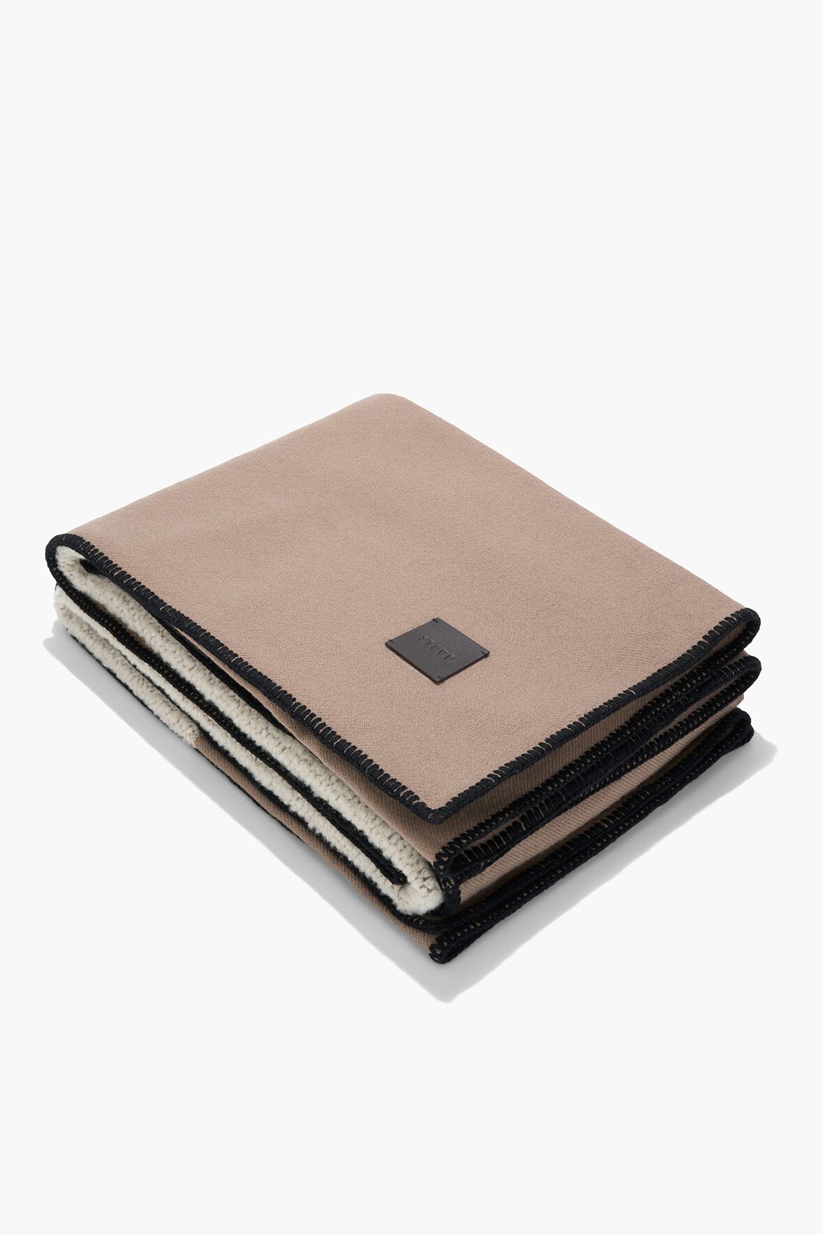 Truffle taupe throw blanket folded with black stitched edging and label
