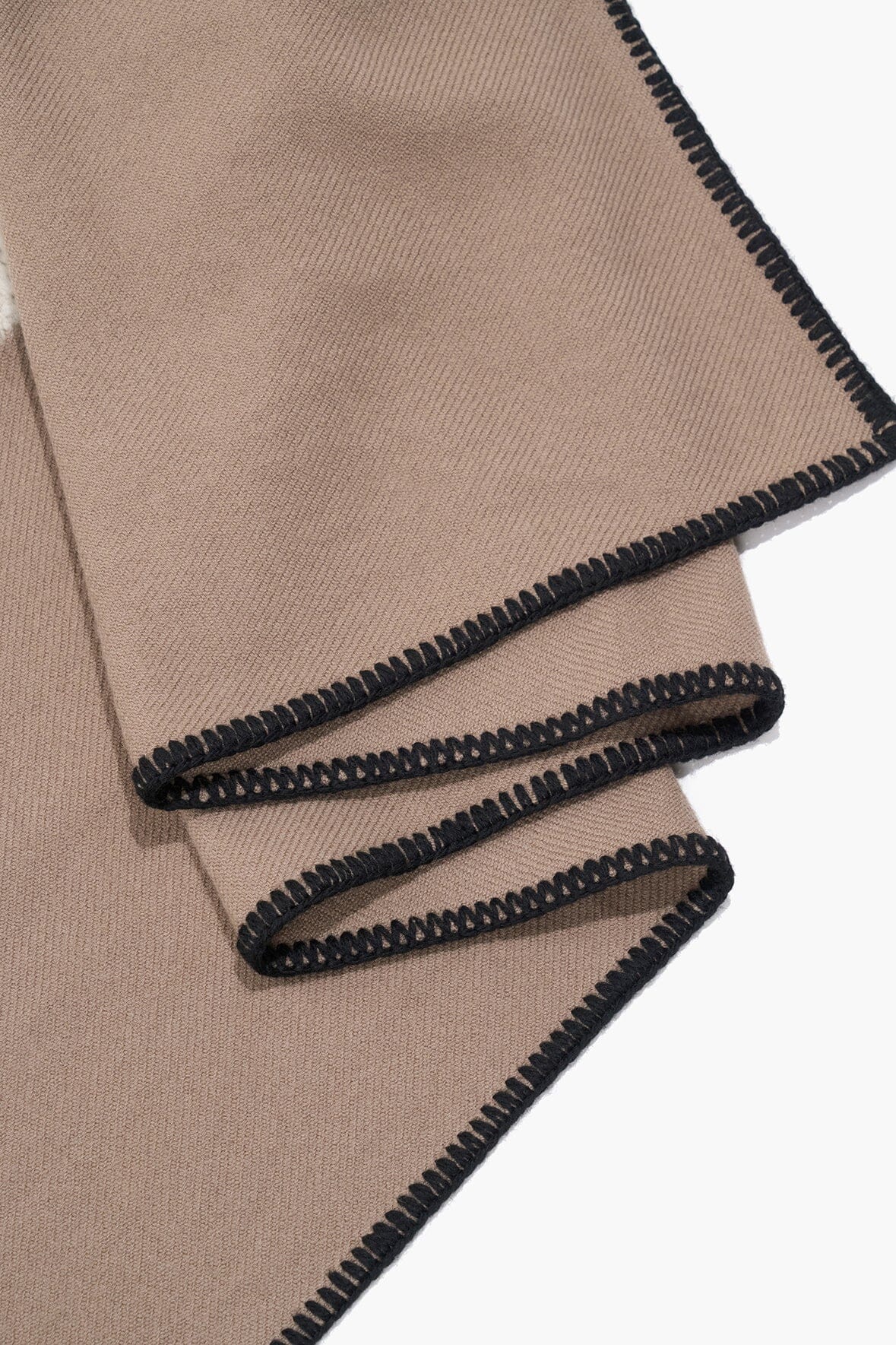 Close-up of truffle taupe throw blanket seam with black stitched border