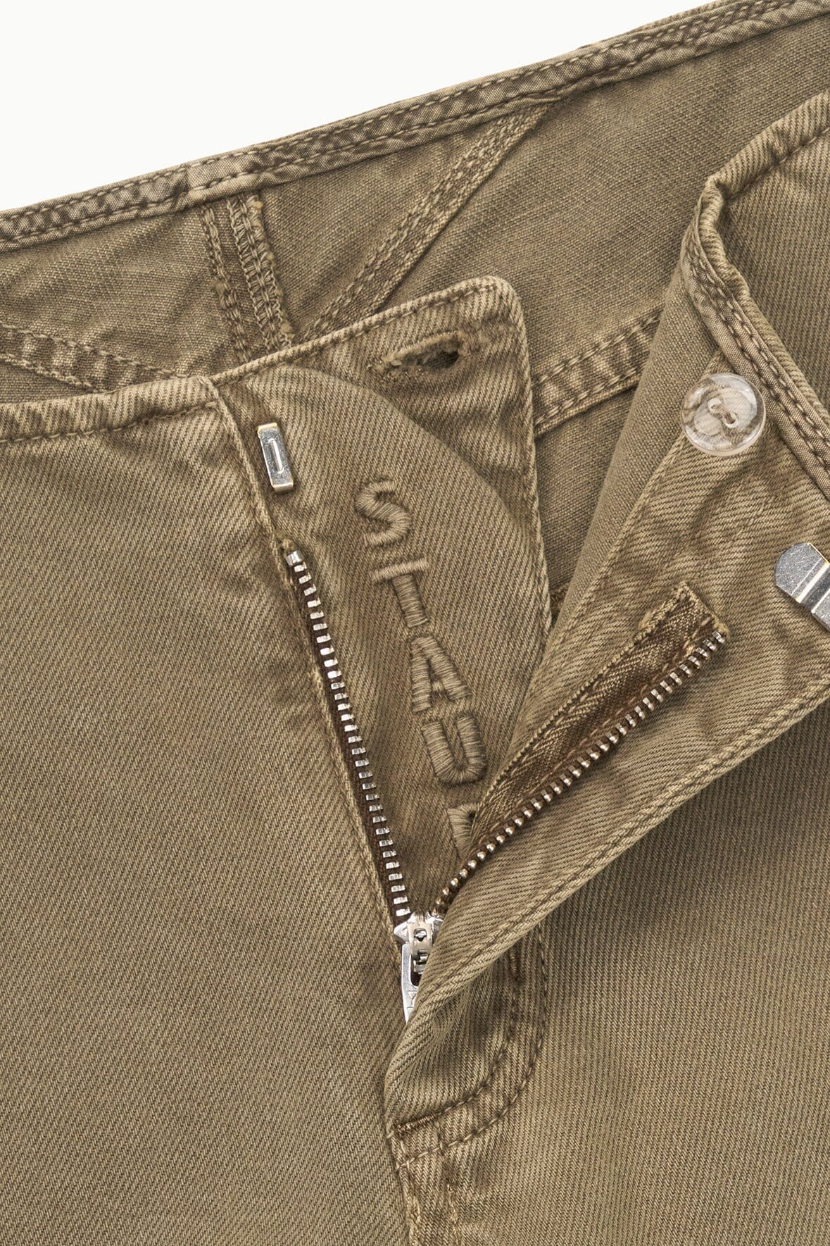 Greige jeans close-up: zipper fly, metal button, and contrast stitching