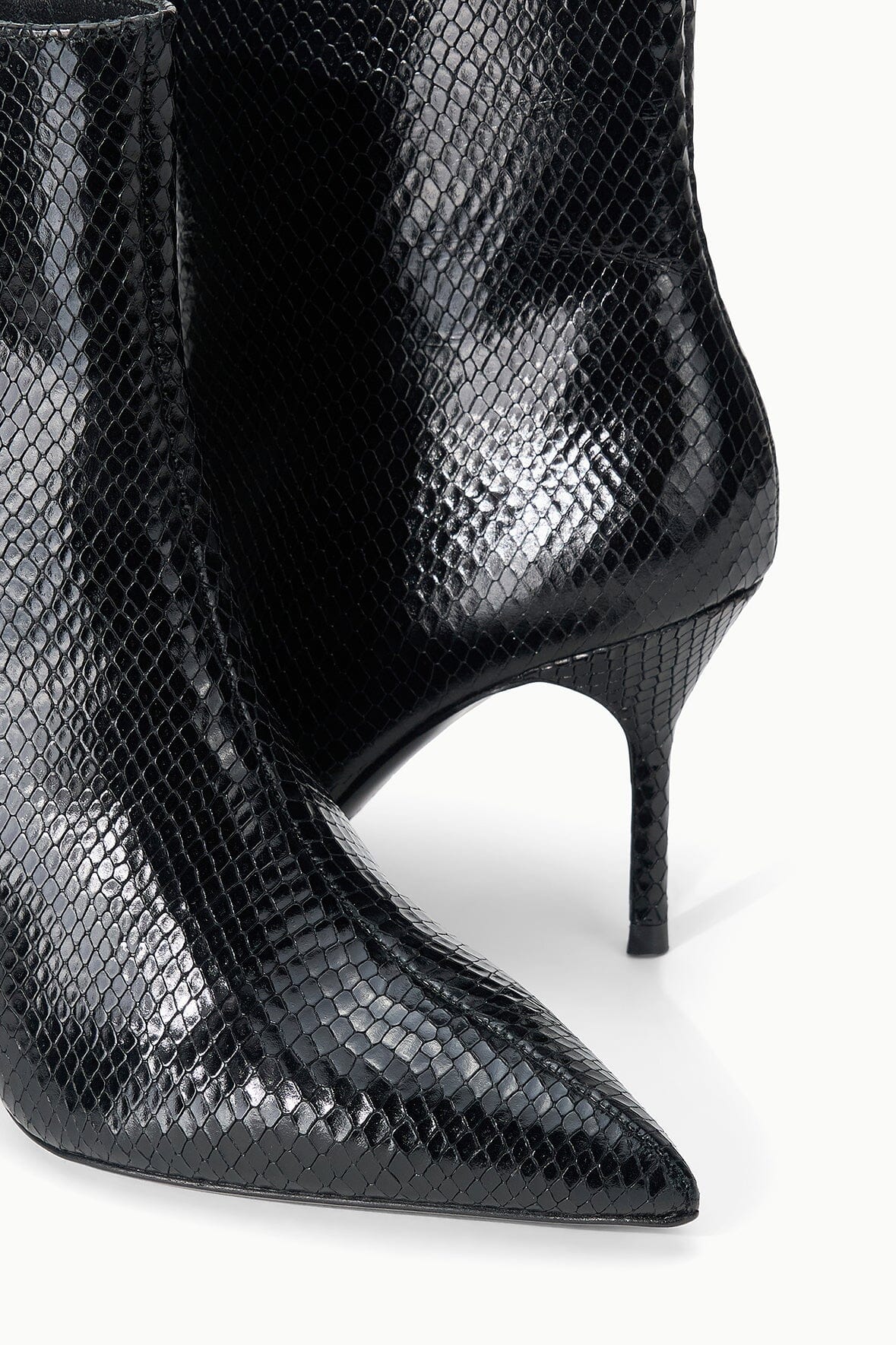 Black snake-print ankle boot close-up, curved stiletto heel