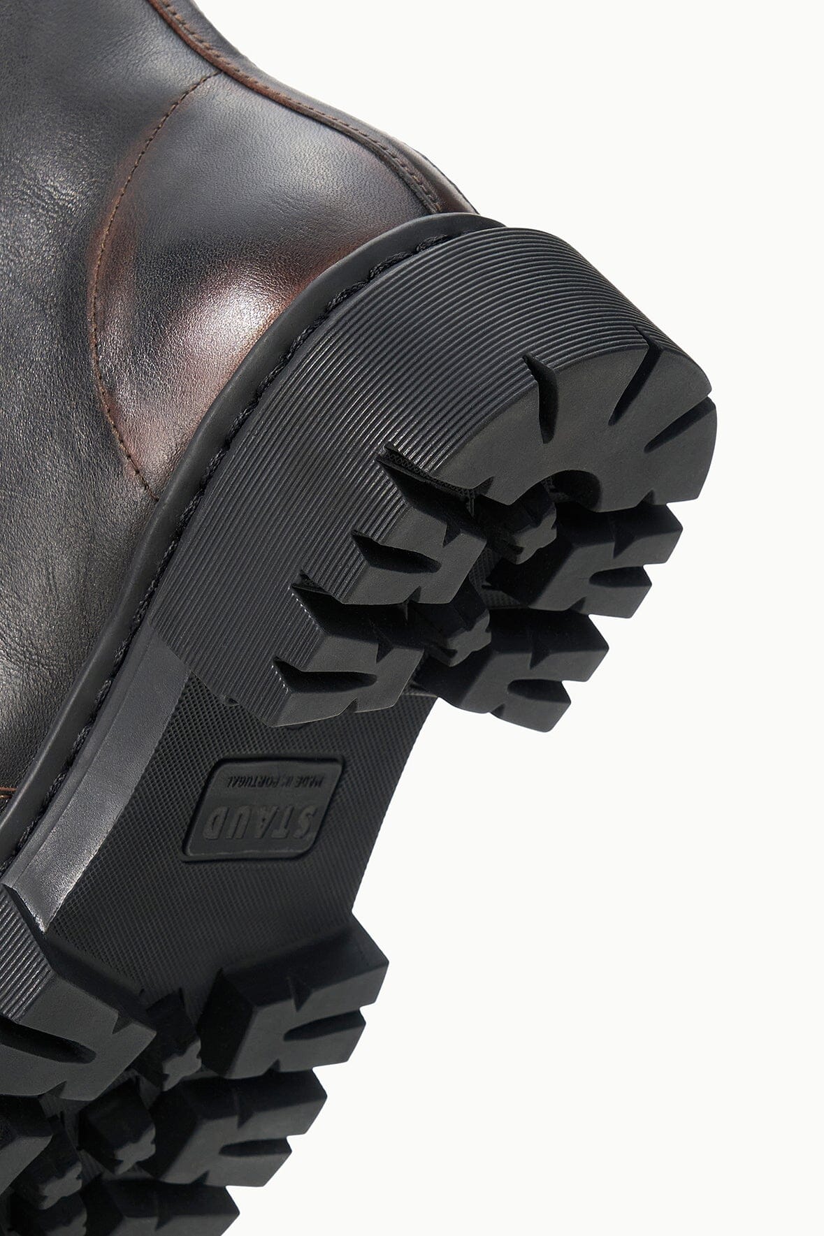 Zip ankle boot outsole view with thick black lug tread and embossed brand mark