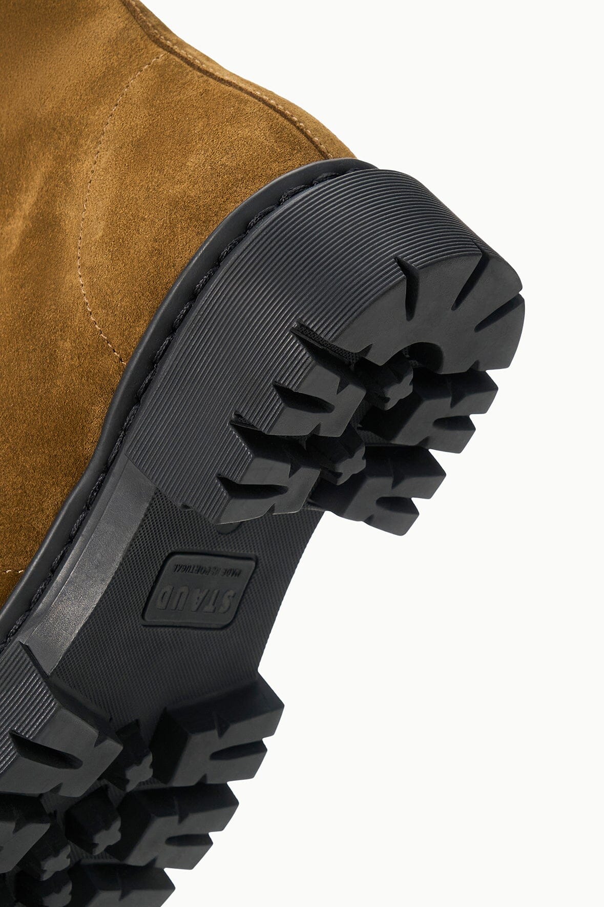 Chunky black lug outsole with deep ridged tread on cigar-brown ankle boot