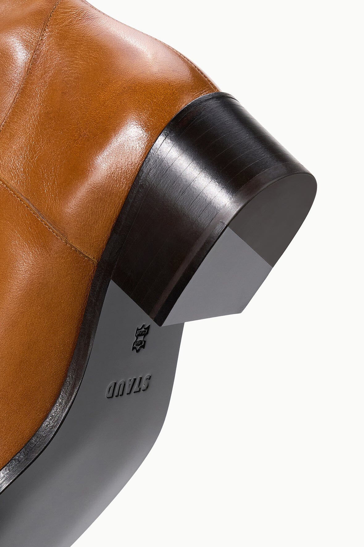 Cashew brown over-the-knee boot heel with black rubber sole and logo detail