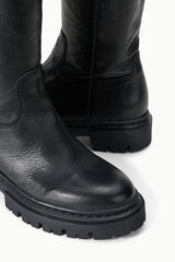 Black tall leather boot detail with stitched ankle seam and lug tread sole