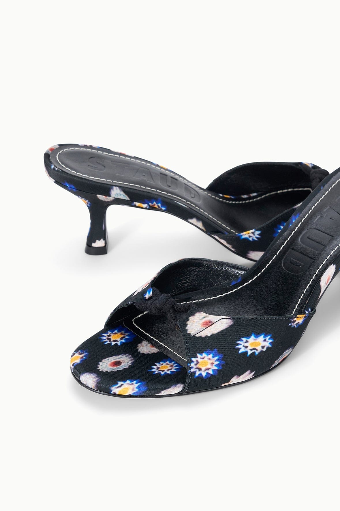Black floral mule with low kitten heel, close-up of printed fabric upper