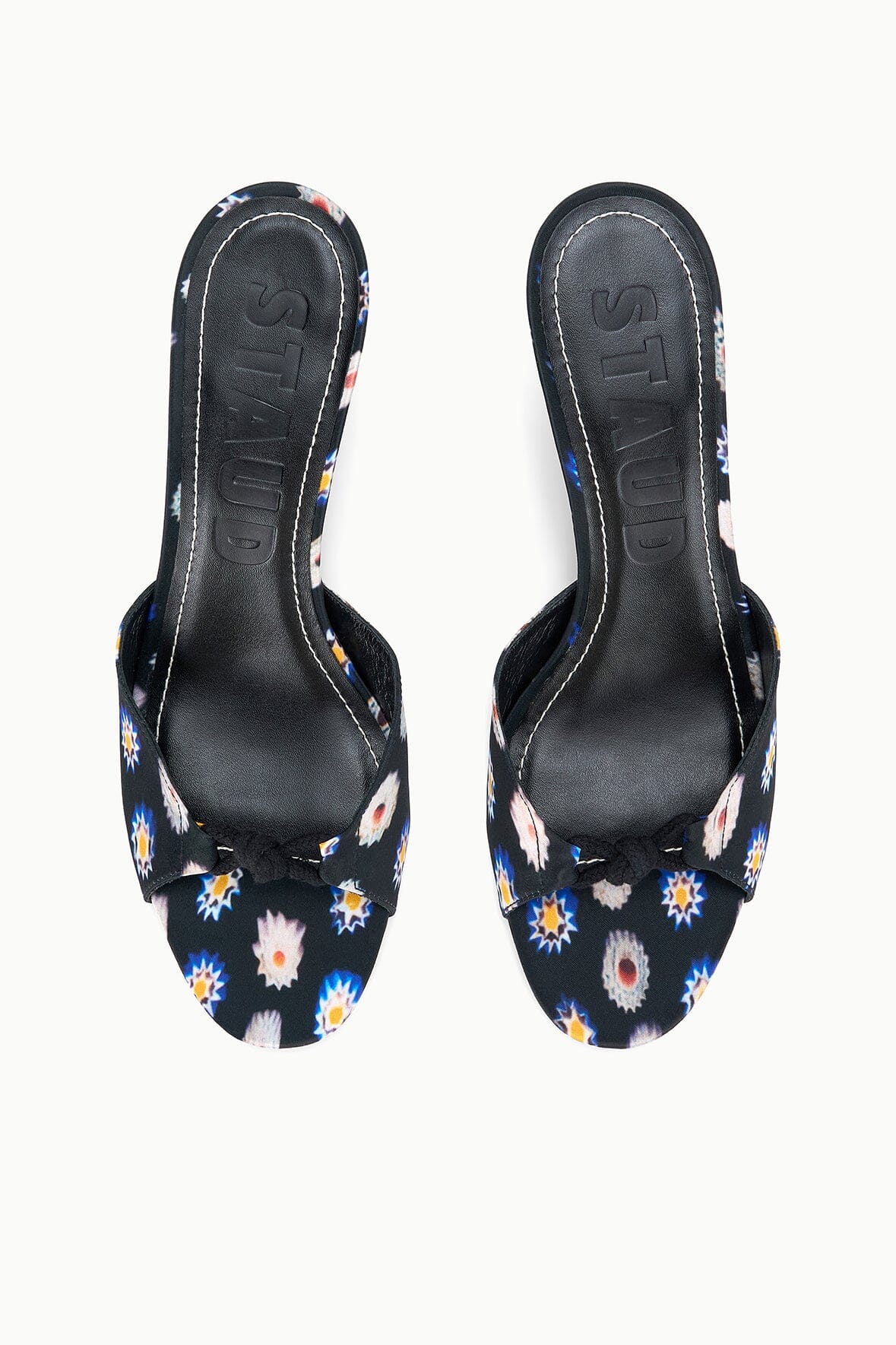 Pair of black floral mules with low kitten heel, slip-on style and patterned toe