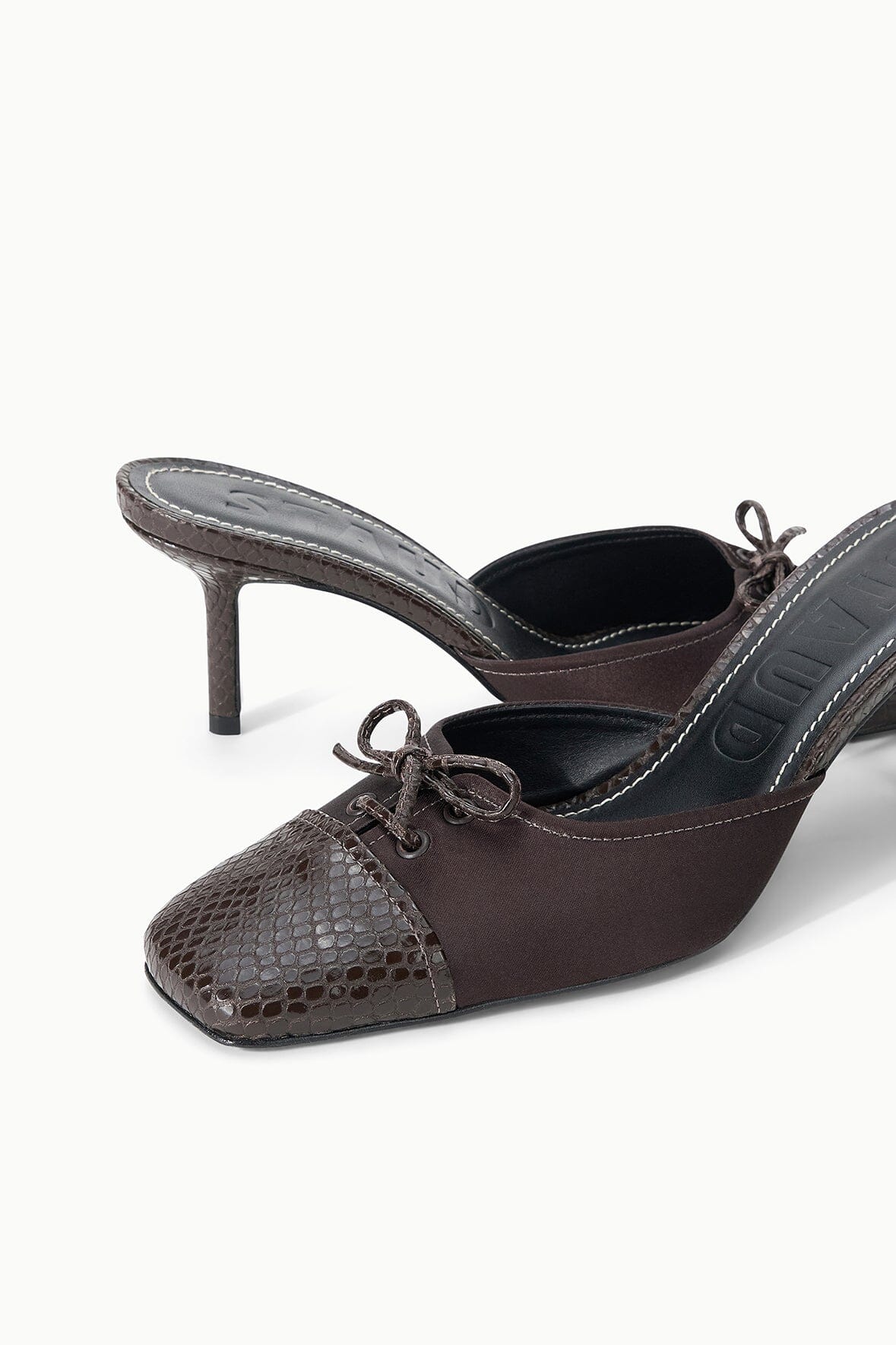 Pair of espresso mules with lace-up front, snake-texture toe, and stiletto heels.