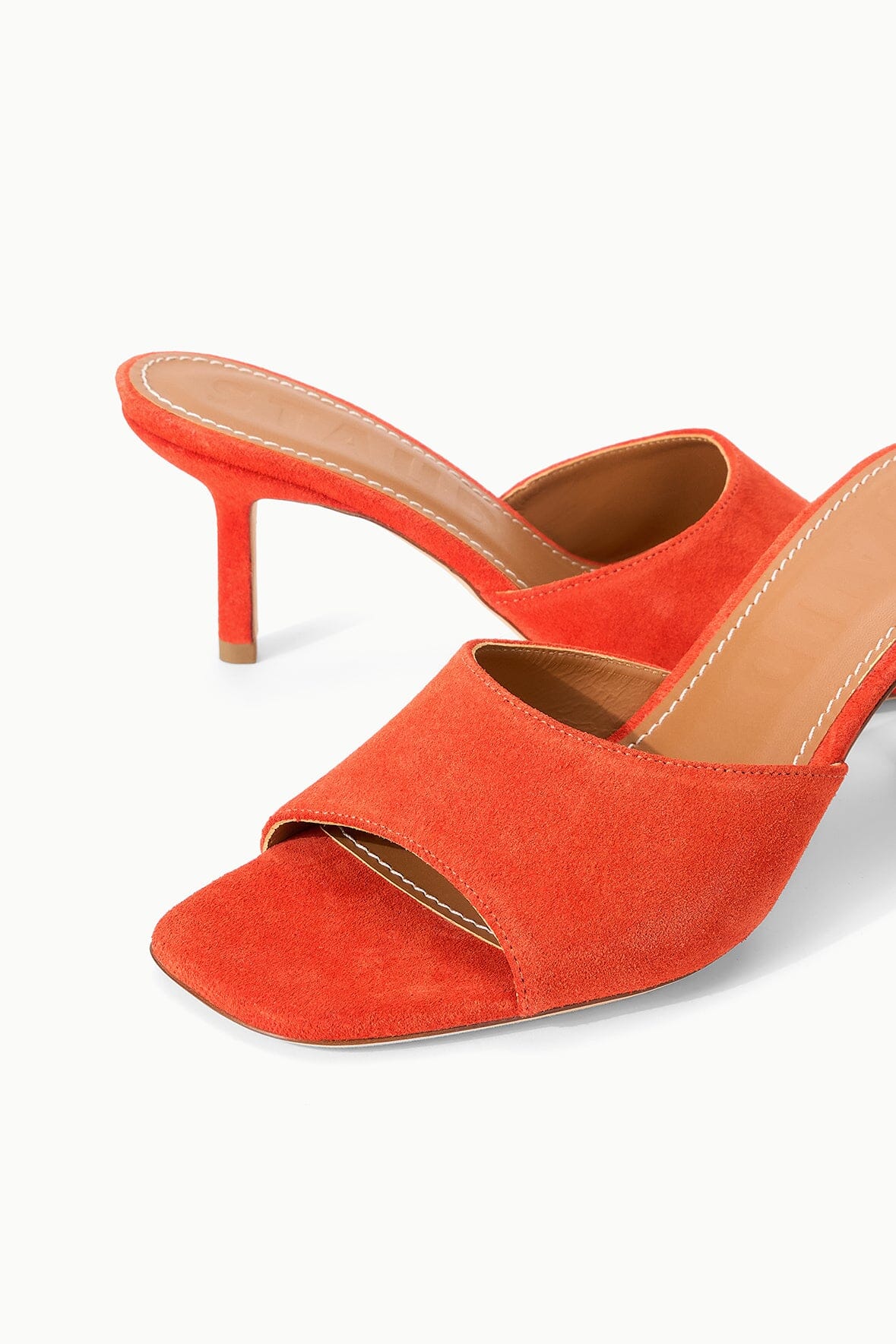 Pair of orange suede open-toe mules with slim stiletto heels and crossover upper.