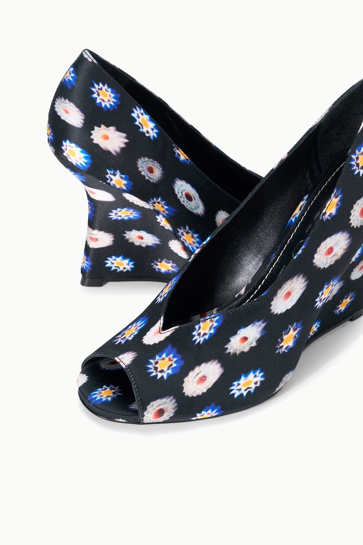 Angled view of peep-toe wedge heel shoes with floral pattern fabric