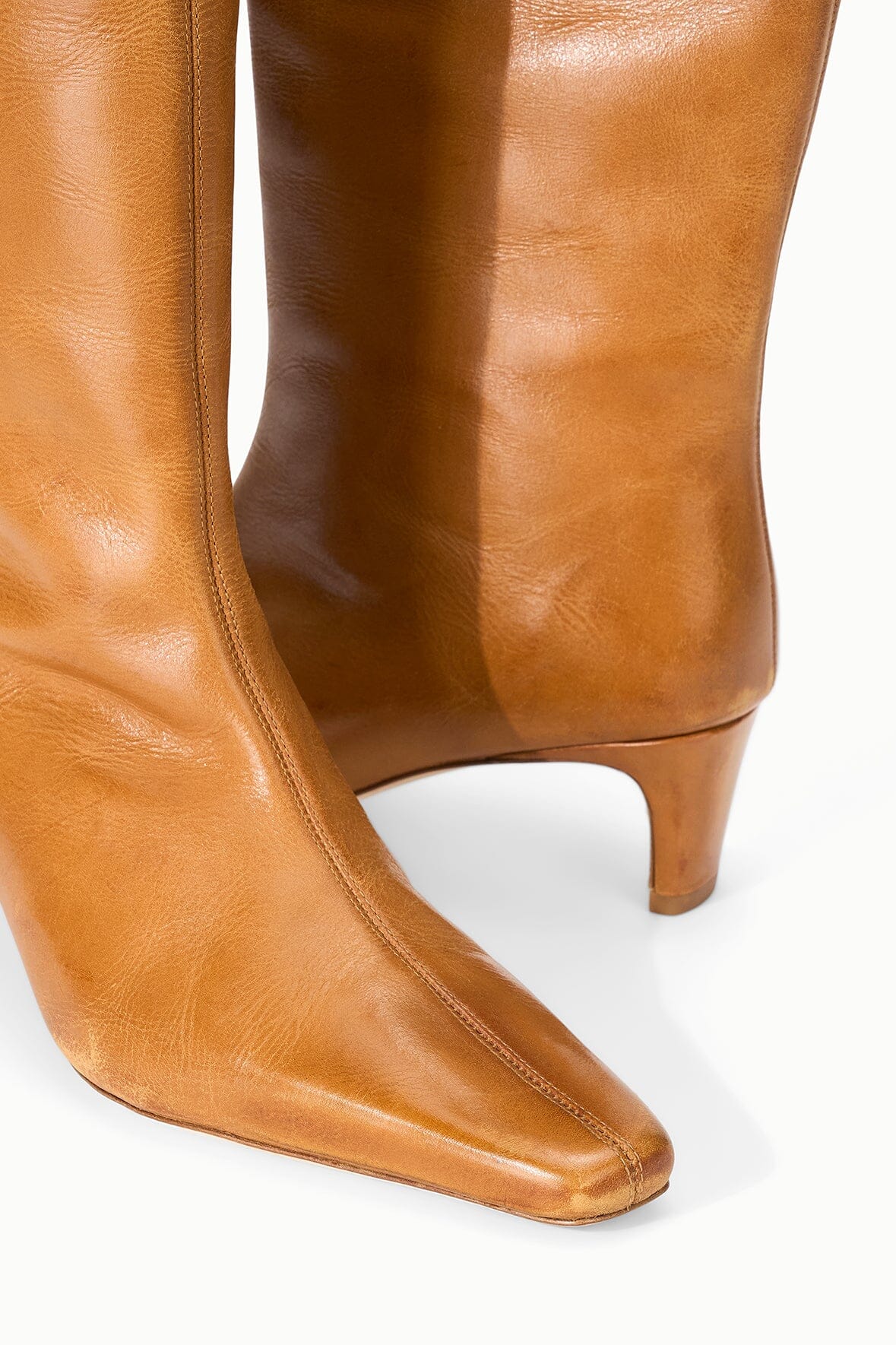 Cashew distressed knee-high leather boot, side view with pointed toe and low heel