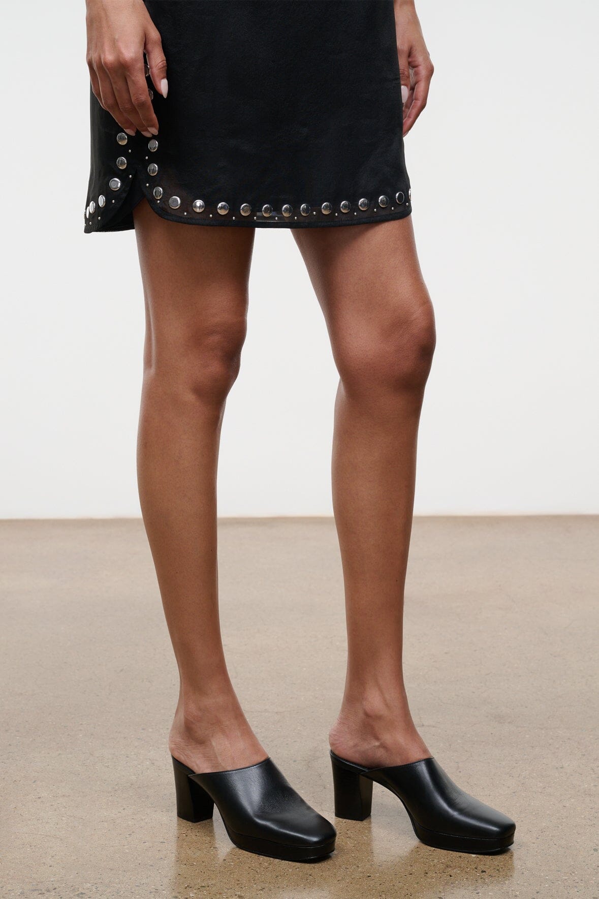 Black mule clogs with block heel, side view on model