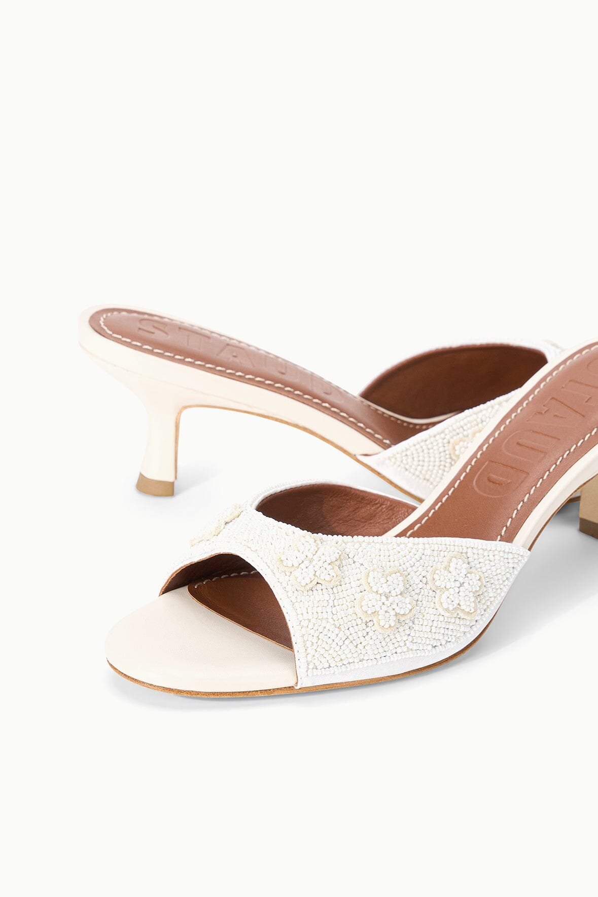 Close-up of white textured open-toe mule with peep opening and mid-height heel