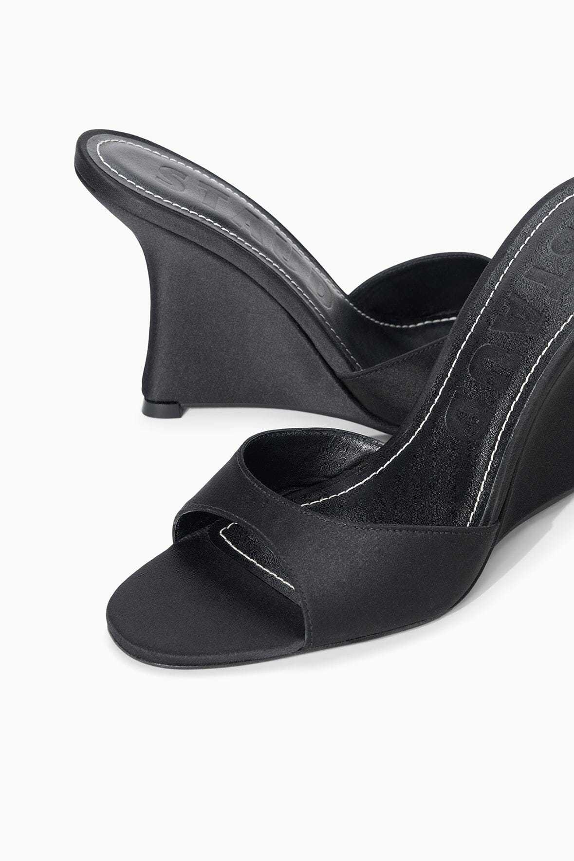 Black satin high-wedge slide sandals, close-up of open toe and wedge heel