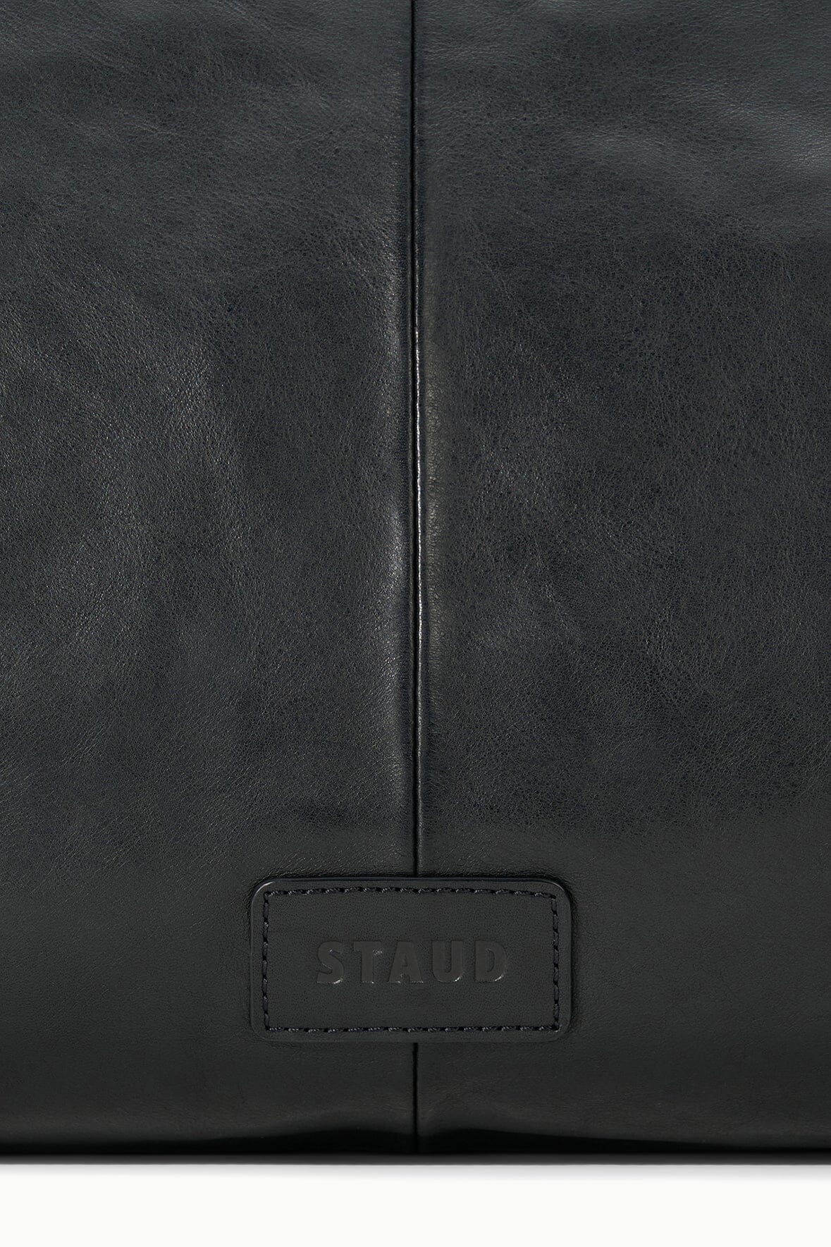 Black leather bag with STAUD logo patch centered on front panel
