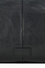 Black leather bag with STAUD logo patch centered on front panel