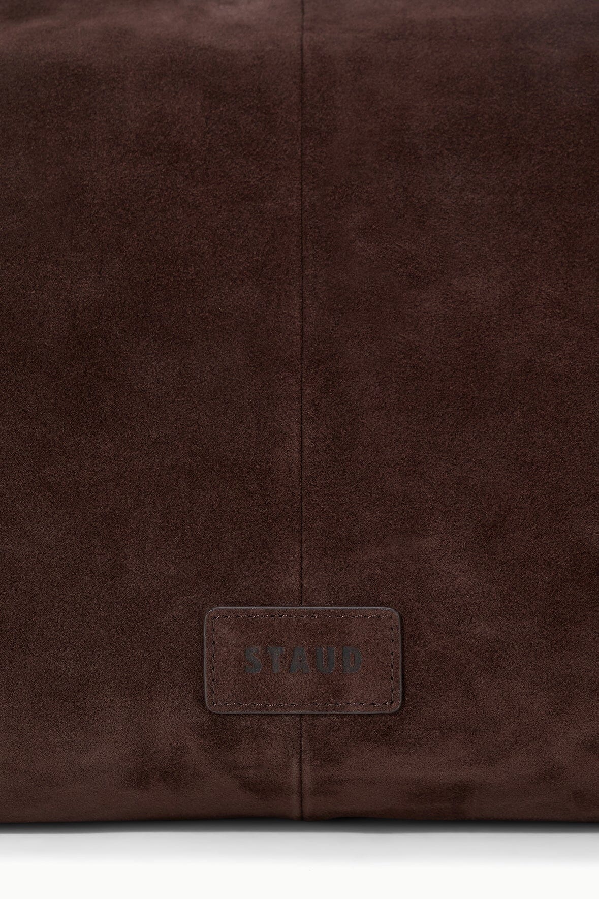 Brown suede handbag close-up of rear logo patch