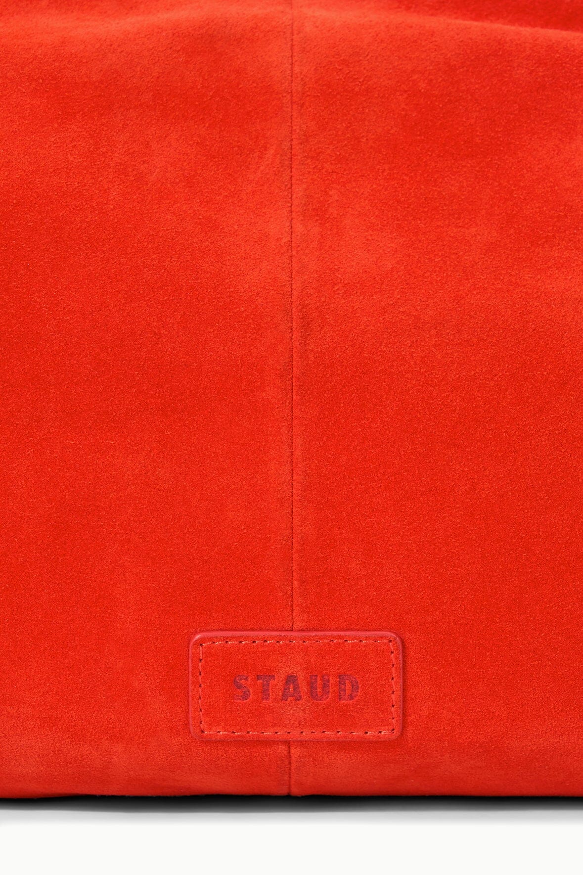 Tangerine-orange bag with front logo patch labeled STAUD on the lower panel.