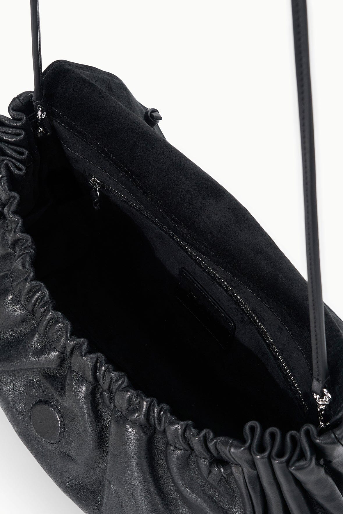 Black convertible bag close-up showing inner zip pocket and ruched edge