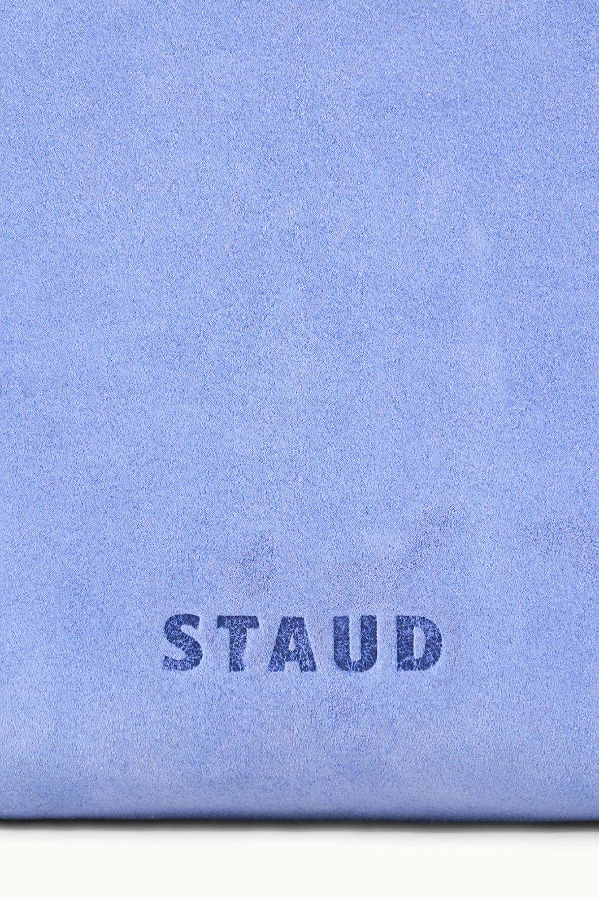 Light blue fabric close-up with 'STAUD' logo printed on the front