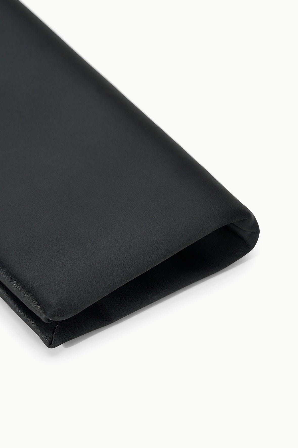 Black clutch bag corner close-up with folded edge and smooth lining