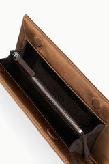 Tan leather clutch bag interior with zip pocket and drawstring pouch.