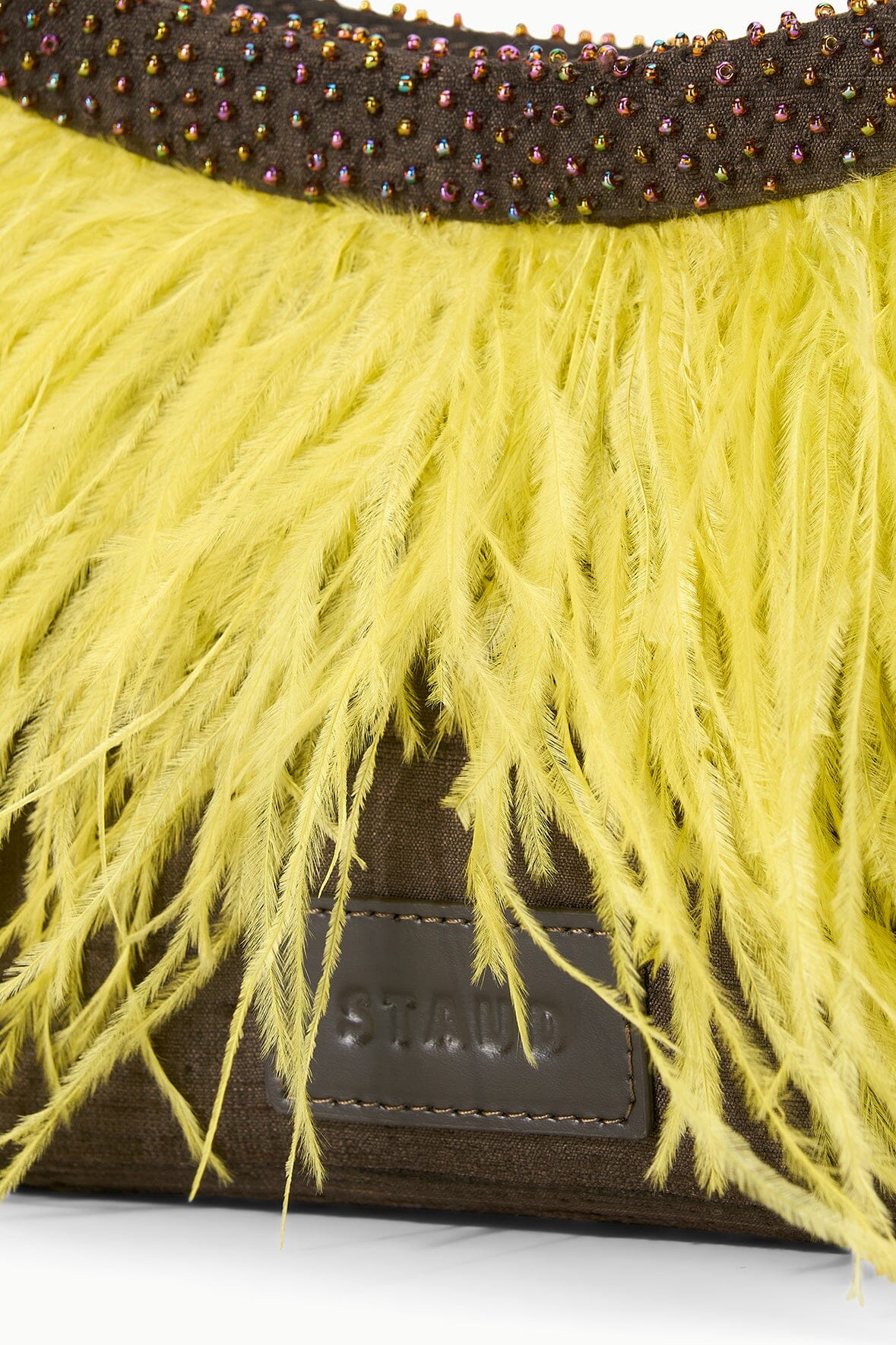 Close-up of yellow fringe mini bag showing dark beaded trim and brown leather base.