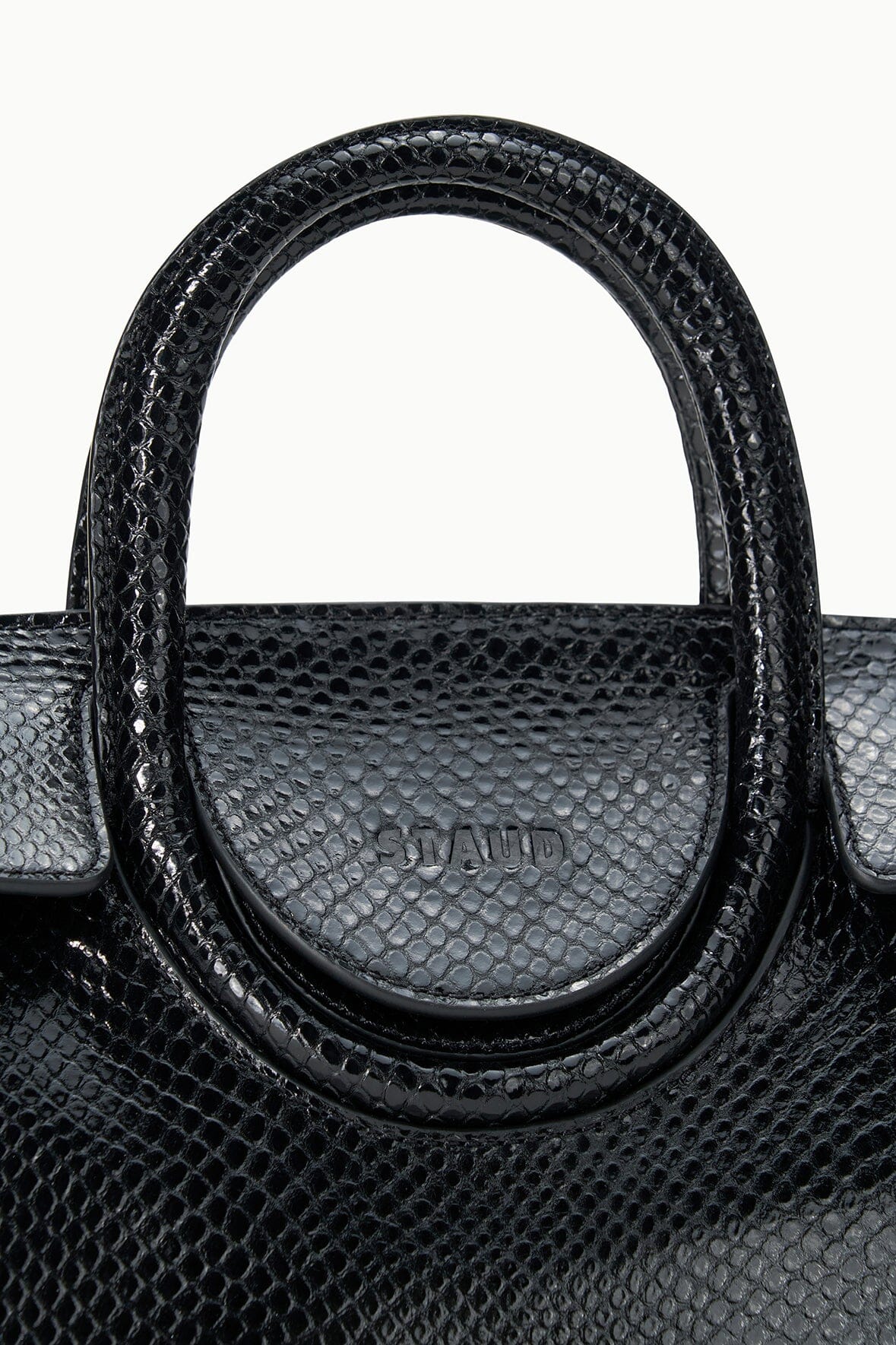 Maude mini carryall bag close-up: curved handle on dark textured leather