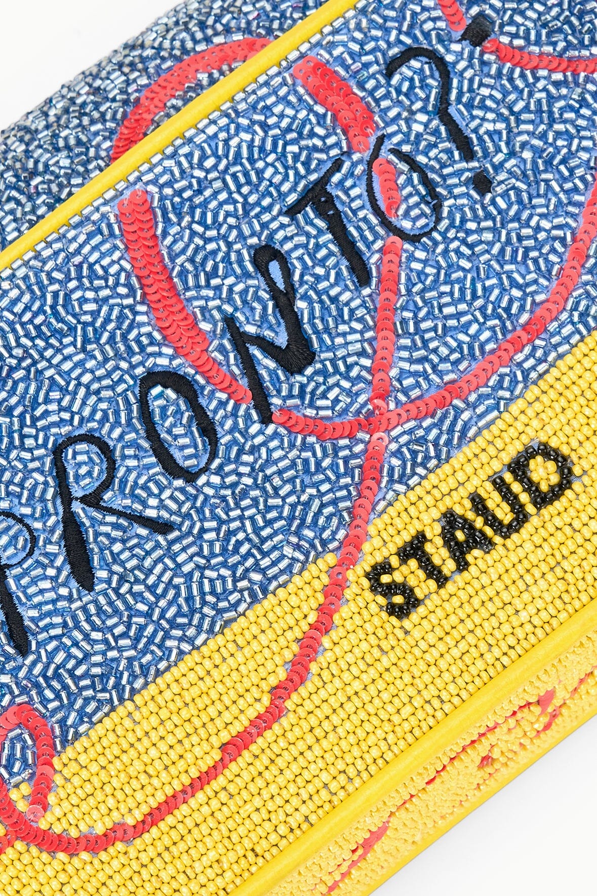 TOMMY beaded bag close-up, blue bead texture with 'HOTLINE' on yellow stripe.