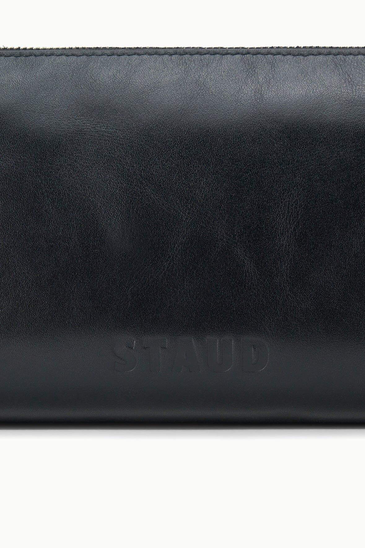 Black leather shoulder bag close-up with embossed logo on front