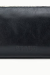 Black leather shoulder bag close-up with embossed logo on front