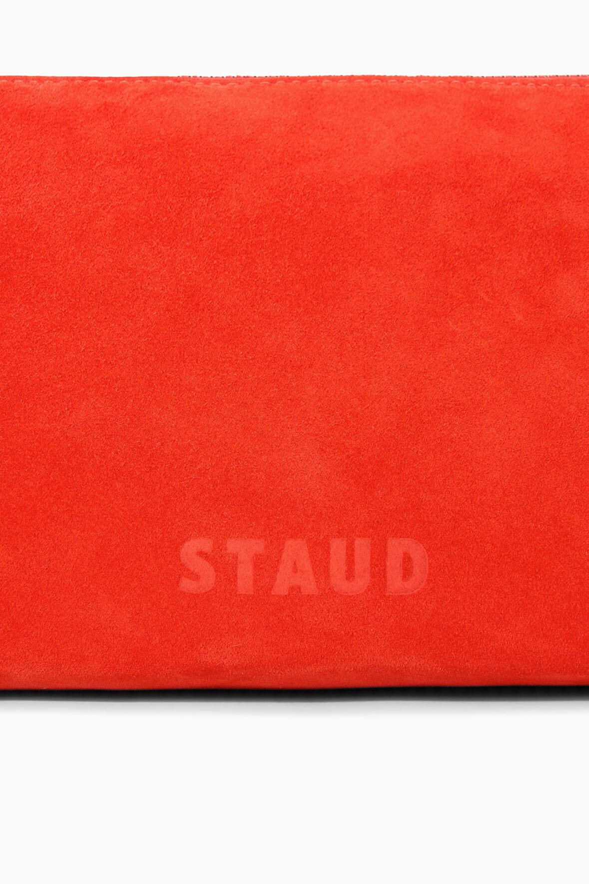 Orange suede-like shoulder bag panel with embossed “STAUD” logo