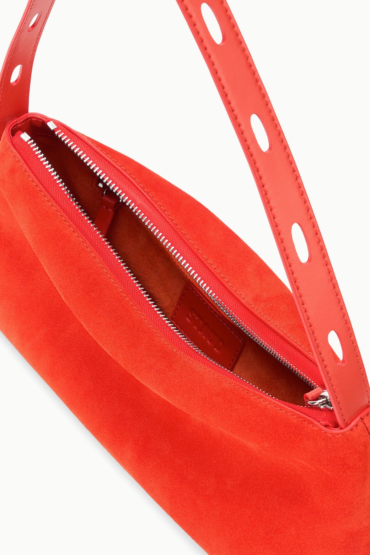 Orange shoulder bag showing dual zipper openings and red-lined interior
