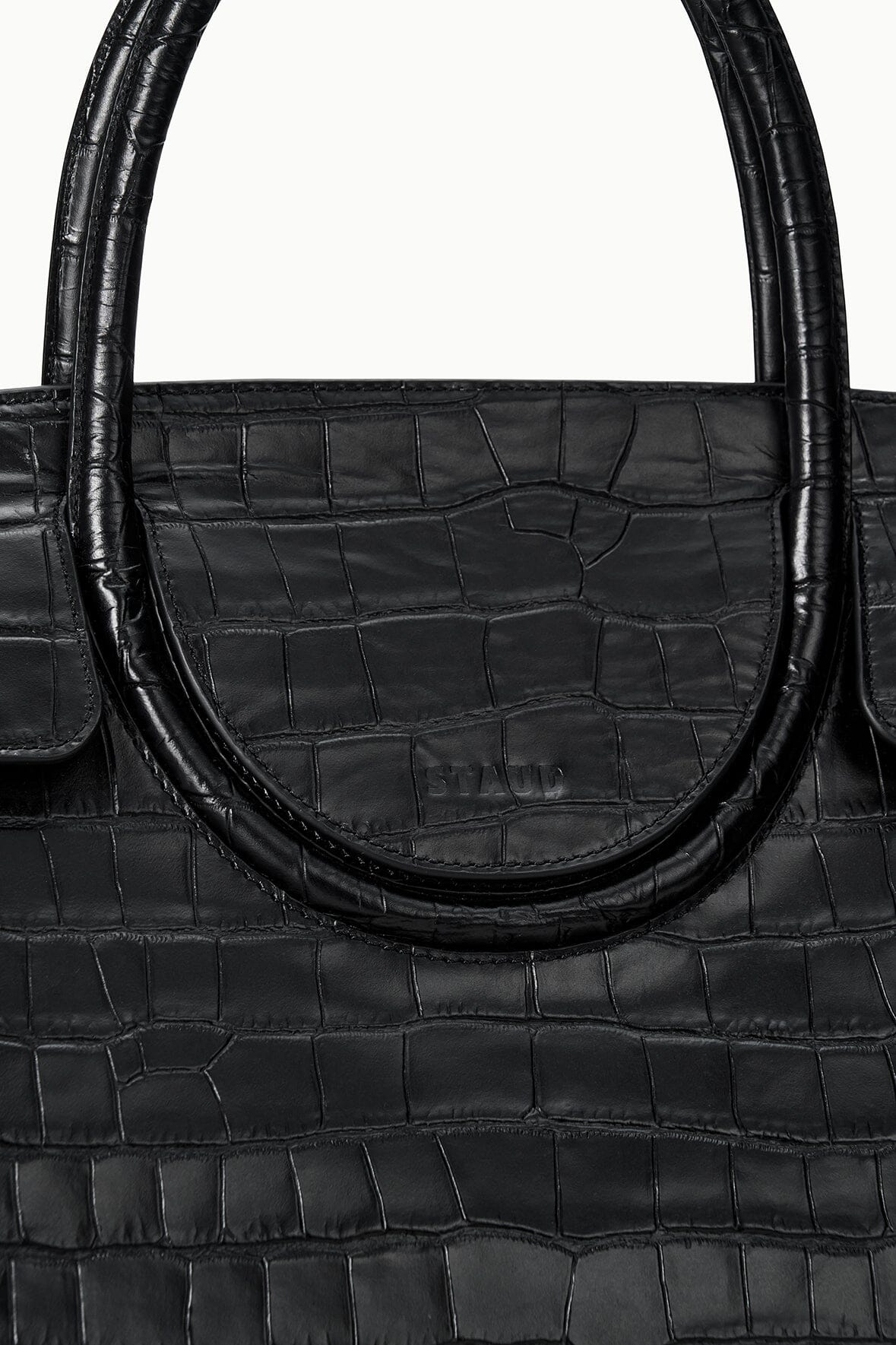 Black croc-embossed bag close-up of curved handle and stamped logo
