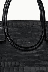Black croc-embossed bag close-up of curved handle and stamped logo