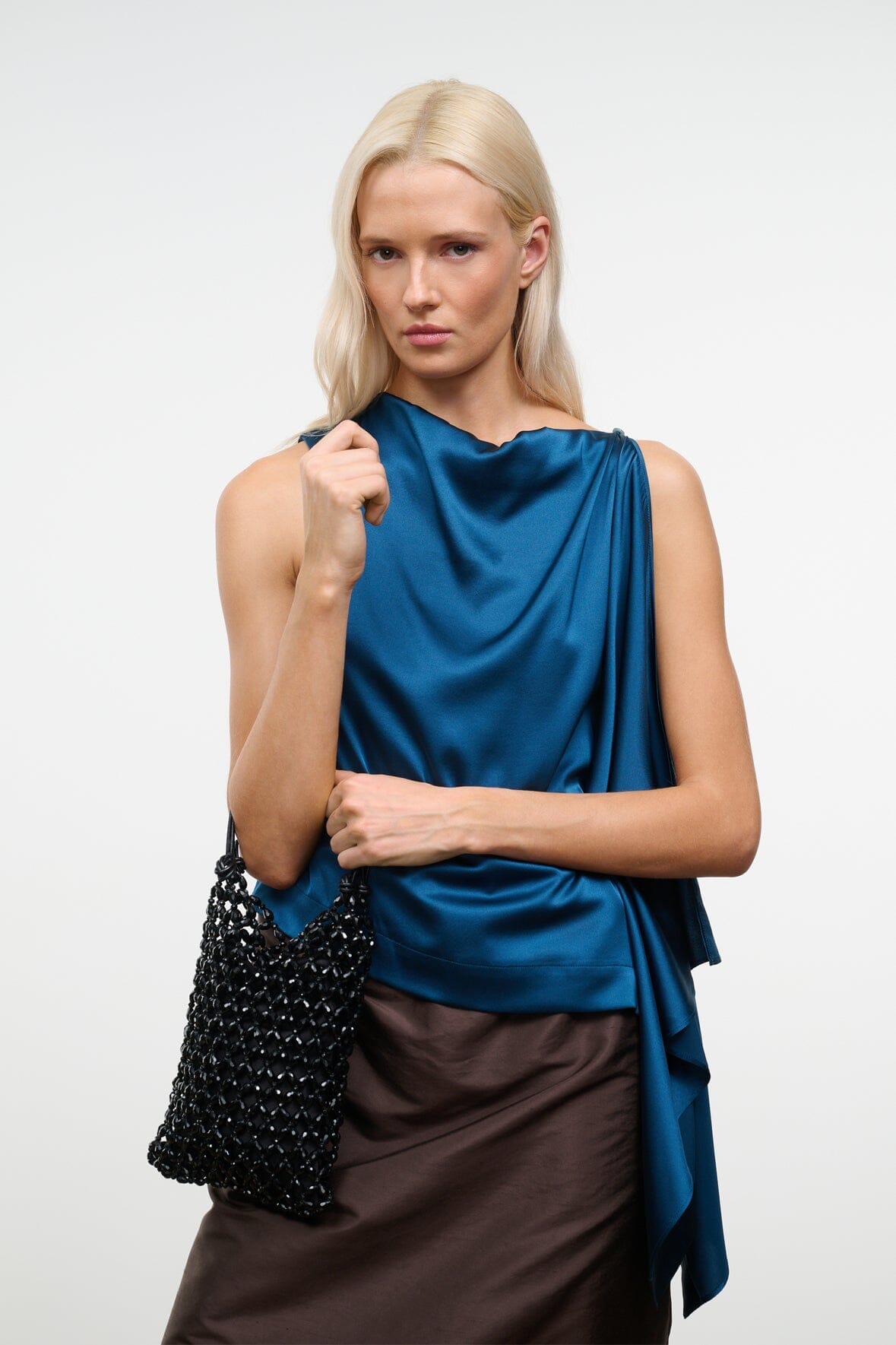 Black beaded mini tote bag held at shoulder, featuring knotted short handles