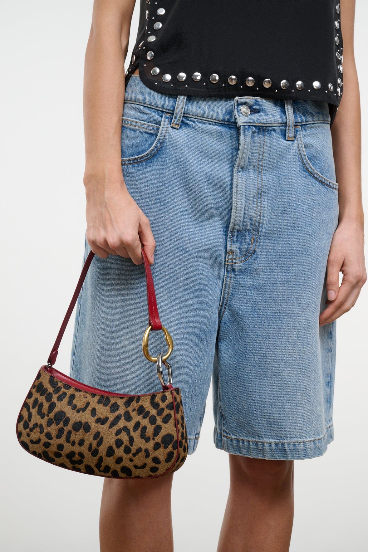 Close view of OLLIE bag on burgundy handle with cheetah print body and gold ring