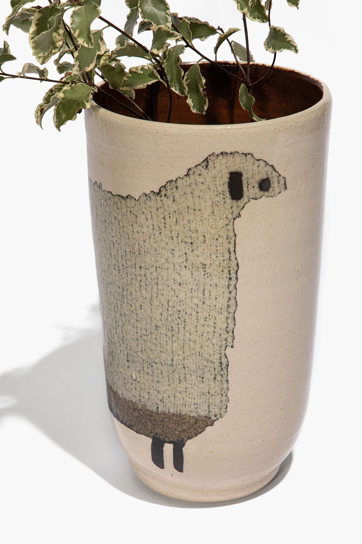 Tall ceramic sheep vase with greenery, dark sheep silhouette on speckled beige