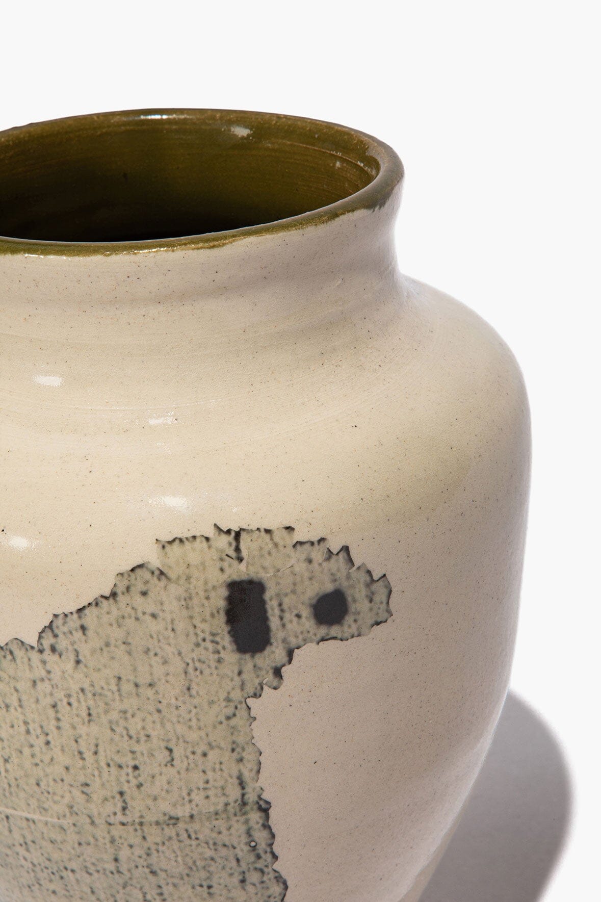 Ceramic vase close-up showing black sheep face silhouette on beige speckled glaze