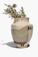 Round ceramic sheep vase with beige body, black sheep silhouette, holding small flowers