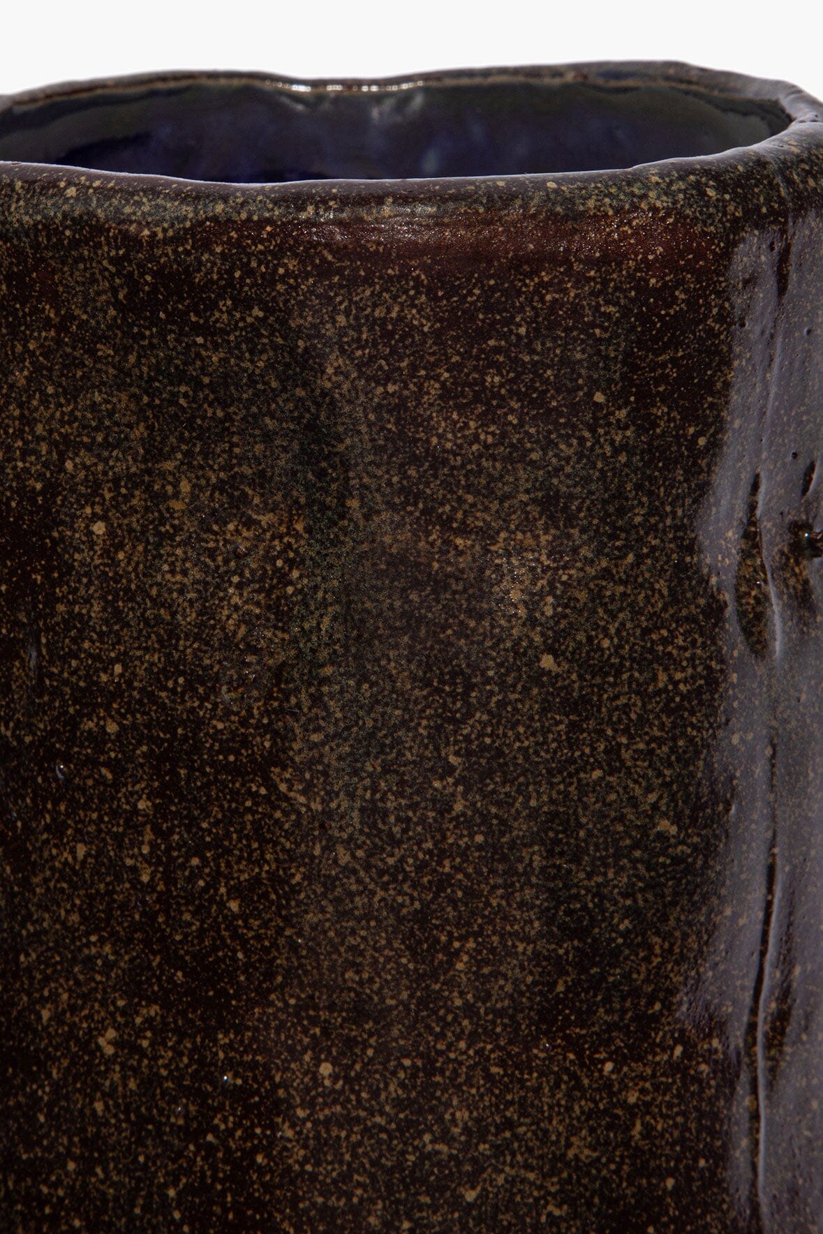 Close-up of dark speckled ceramic candle side with glazed textured speckle