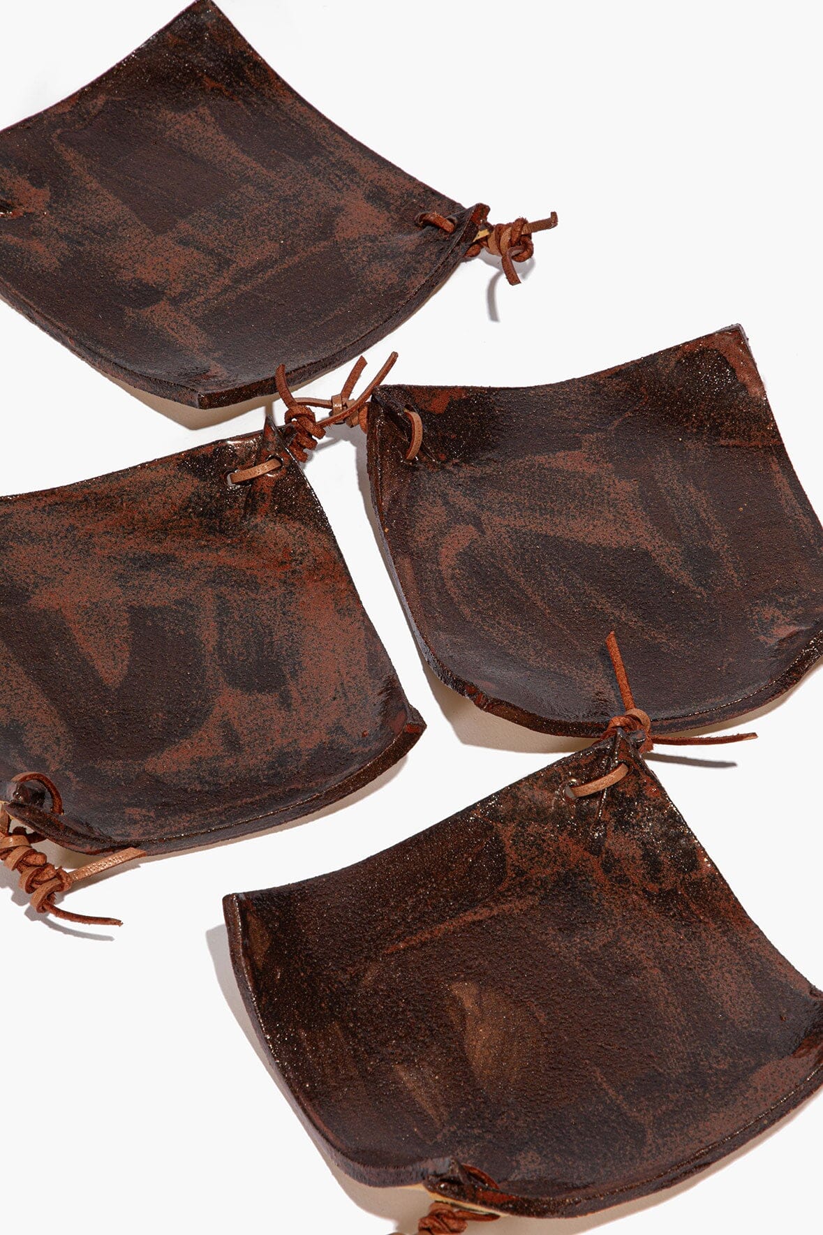 Set of square ceramic coasters with burnt sienna speckled glaze and tied cord loops