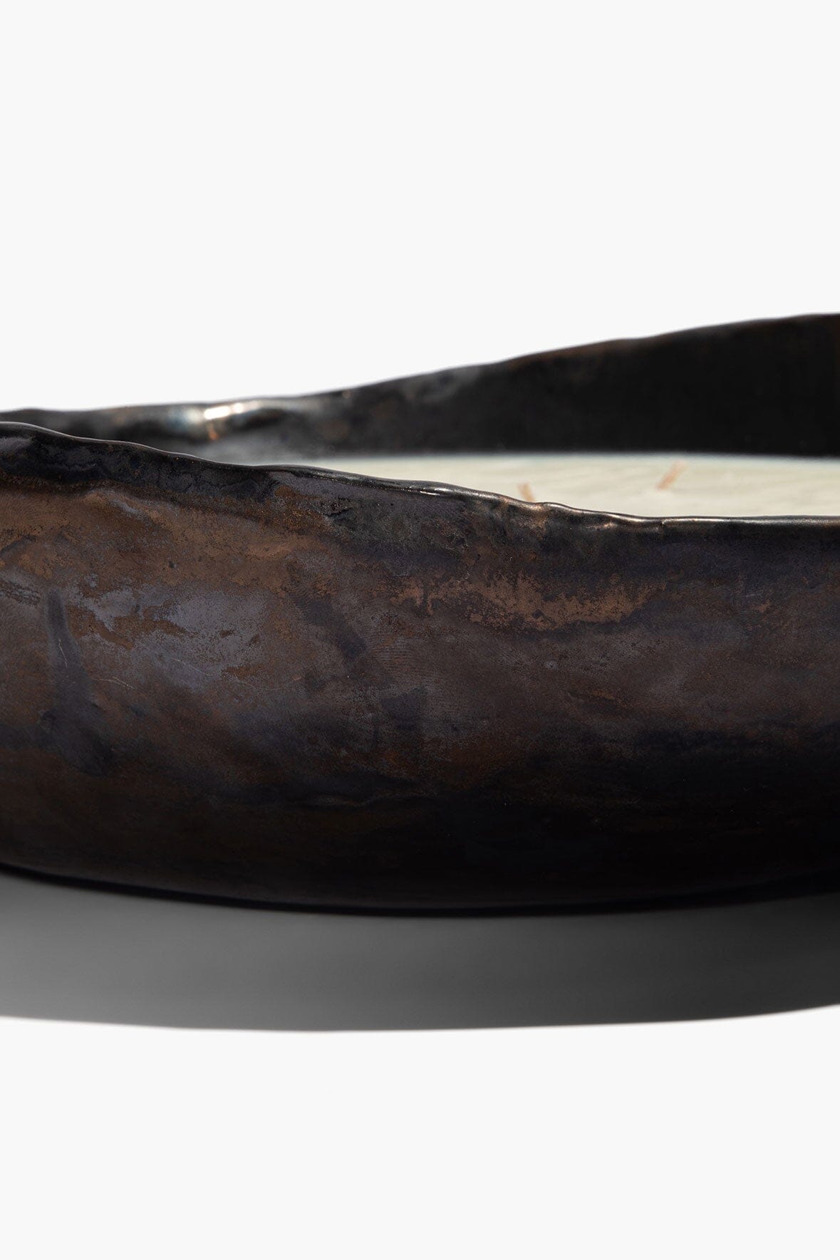 Dark brown ceramic candle bowl with molded texture and white wax rim