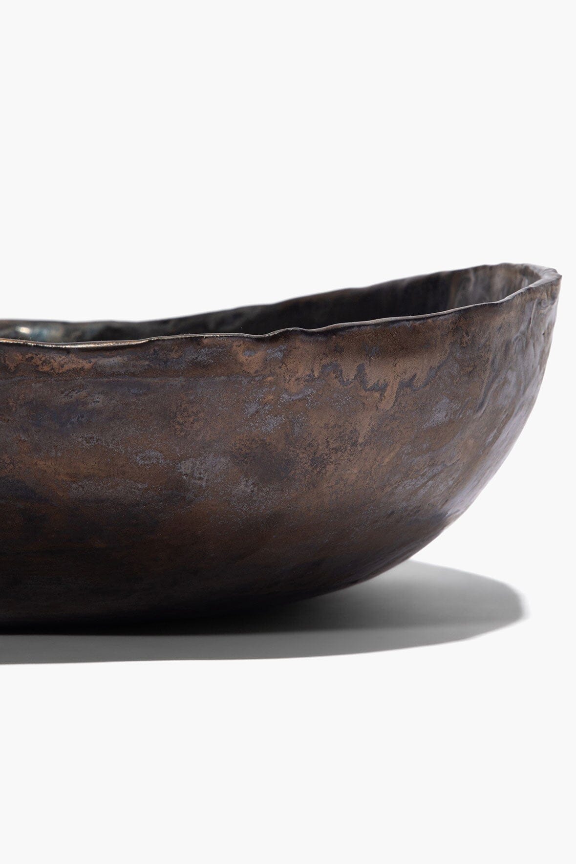 Dark mottled ceramic candle bowl with curved rim and white wax visible