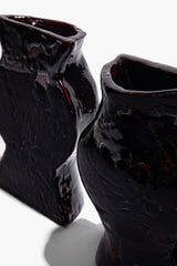 Black glossy ceramic vase bookends, close-up of curved side openings