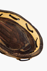 Round ceramic leather-look coaster with studded trim and dark speckled surface