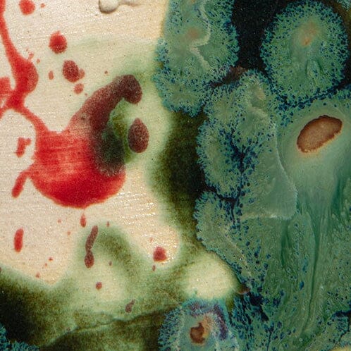Ceramic candle glaze detail with red splatters and blue-green marbled pattern