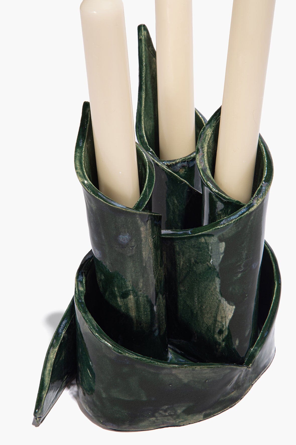 Ceramic triple candlestick holder holding three white candles, forest-green glaze