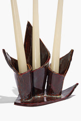 Ceramic triple candleholder in maroon wash glaze, holding three candles with leaf-shaped cups