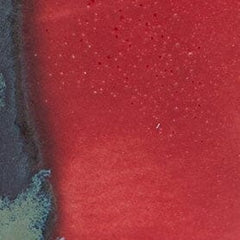 SERRE ceramic candle glaze close-up: red surface with dark teal-blue streaks